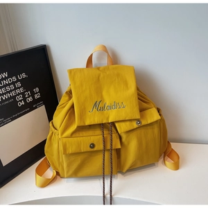 Detail of ginger nylon backpack featuring drawstring closure and blue embroidered logo