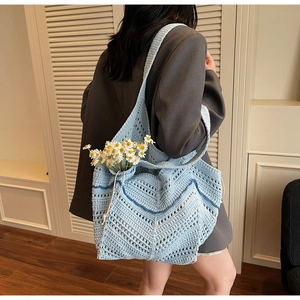 Detail of light blue crochet tote bag with dark blue wavy knit patterns and drawstring