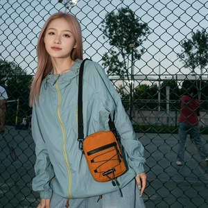 Close-up of orange nylon crossbody bag with adjustable strap and outdoor functional detail