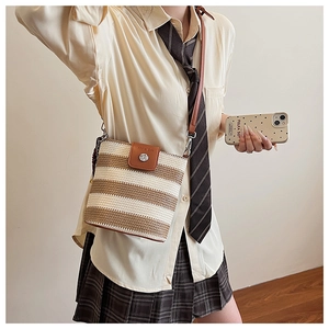 Détail d'un sac seau rayé tissé main avec rabat en cuir marron et fermoir argenté
