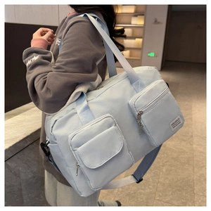 Detail of light blue waterproof nylon travel bag with dual front pockets and shoulder strap