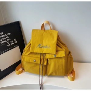 Detail of yellow nylon backpack with front snap pockets and blue Mulaidiss embroidery