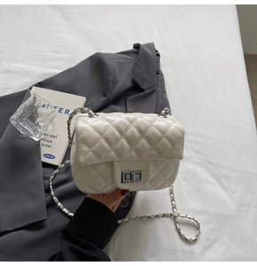 Gros plan d'un sac matelassé beige avec fermoir argenté et accessoires minimalistes