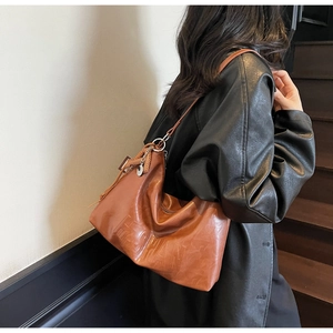Detail of brown PU leather tote bag with FASHAN embossed lettering and metal tassel charm