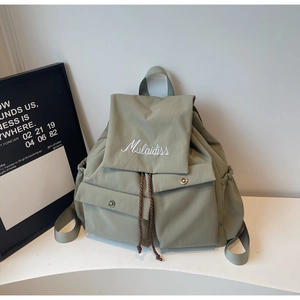 Detail view of the mint green nylon backpack with elegant Mulaidiss script embroidery