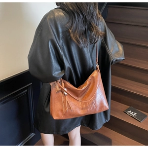 Detail of brown leather hobo bag with HAN embossed texture and stylish fringe charm