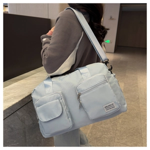 Detail of light blue waterproof travel bag showing front pockets and brand logo