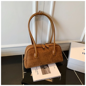 Detail of a brown suede baguette bag with smooth leather handles and dual zipper closure