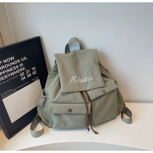 Detail of sage green canvas backpack with Mulaidiss embroidery and metal buckle closures