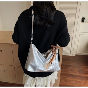 Detailed view of silver hobo bag with H.SHAN embossing and brown leather tassel charm