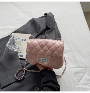 Gros plan du sac rose matelassé avec fermoir rotatif argenté sur veste de costume