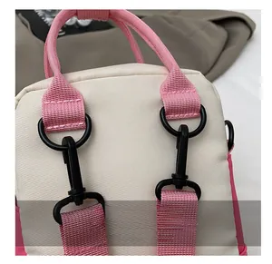 Close-up of durable black rotating carabiner hooks on beige canvas bag with pink straps