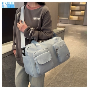 Macro detail of the light blue travel bag showing durable nylon texture and side pockets