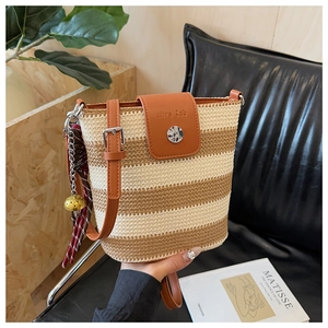 Détail du sac seau tissé à rayures avec rabat en cuir et foulard en soie à fleurs