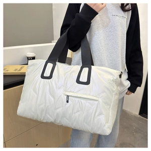 Detailed shot of white quilted travel tote bag with black straps and zipper pocket