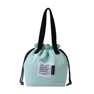 Mint green drawstring lunch bag with black handles and artistic fabric label