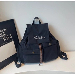 Detail view of black nylon backpack with drawstring closure and Mulaidiss embroidery