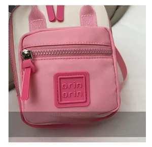 Close-up of pink and beige canvas bag showing zipper detail and rubber brand logo