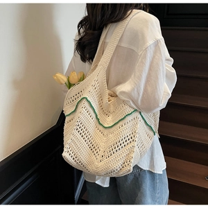 Detail of hand-crocheted tote bag with cream knit patterns and green scalloped edges