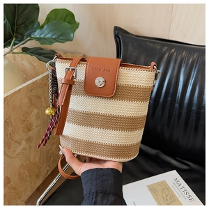 Détail du sac seau en paille arc-en-ciel avec rabat en cuir et breloque clochette