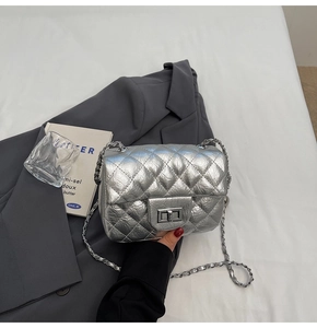 Détail du sac argenté matelassé avec fermoir rotatif en métal et bandoulière en chaîne