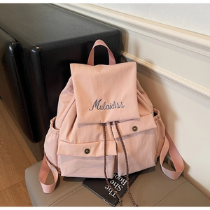 Detail of pink nylon backpack with embroidered brand logo and vintage metal buckles
