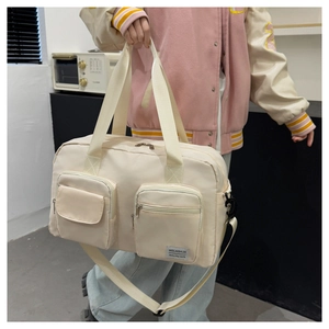 Detail of off-white travel bag featuring functional zip pockets and durable nylon texture