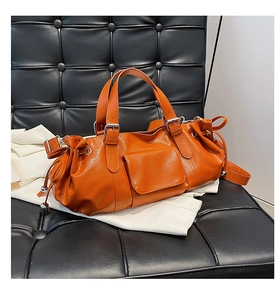 Detail of orange pleated baguette bag with silver hardware and drawstring side accents