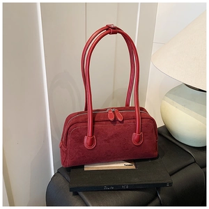 Detail of red suede baguette bag featuring white contrast stitching and double zippers
