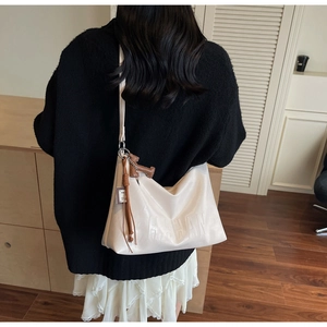 Detail of hobo shoulder bag with embossed letters, brown tassels and decorative charms