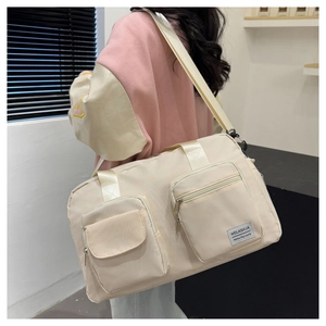 Macro detail of the creamy white nylon travel bag with exterior zipper pockets