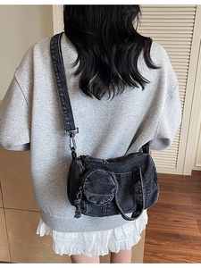 Minimalist black denim crossbody pillow bag with small detachable coin purse on a model