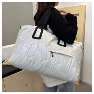 Macro detail of the white quilted travel tote bag featuring black wide nylon handles