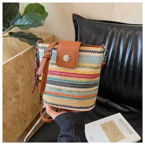 Détail du sac seau en paille tissée à rayures colorées avec rabat en cuir marron et boucle