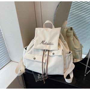 Detail of cream canvas backpack with drawstring closure and Mulaidiss embroidered logo