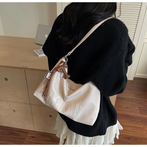 Detail of off-white hobo bag showing H.SLAN embossed logo and brown letter pendant