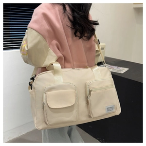Detail of beige travel bag showing dual front pockets and adjustable shoulder strap