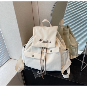 Detailed back view of off-white canvas backpack with mirror reflection and drawstring closure