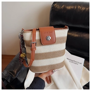Détail du sac seau tissé arc-en-ciel avec rabat en cuir marron et pendentif perlé
