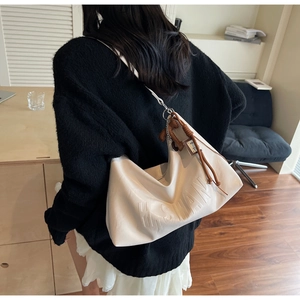 Detail of beige textured tote bag featuring embossed H.SWAN lettering and shoulder strap