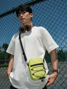 Neon green nylon crossbody bag with adjustable strap and bungee cord detail