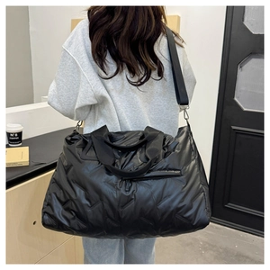 Detail of black quilted puffer tote bag with adjustable strap shown in daily casual use