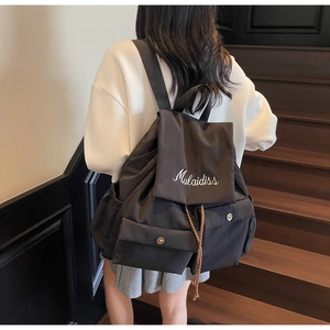 Detail shot of black casual backpack featuring Mulaidiss cursive embroidery on the flap