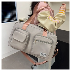 Close-up of a grey waterproof travel bag with pink straps and multi-pocket design