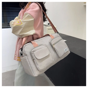 Detail view of large capacity gray travel bag with pink straps worn by a model