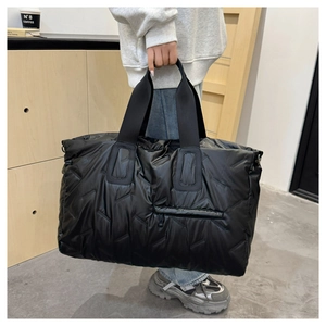 Detail of black quilted travel tote showing large capacity and glossy padded texture