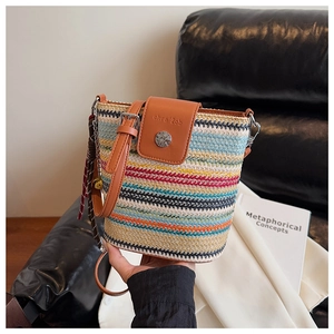Détail du sac seau tissé multicolore avec rabat en cuir et accessoire à pompons bruns