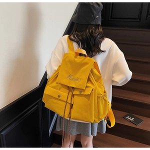 Detailed back view of a large bright yellow canvas backpack on a vintage wooden staircase
