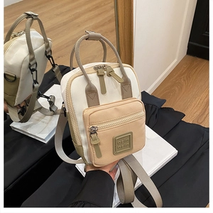 Detailed view of mini two-tone crossbody bag with canvas texture and dual zippers