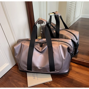 Detail of expandable travel bag with champagne pink water-resistant fabric and logo
